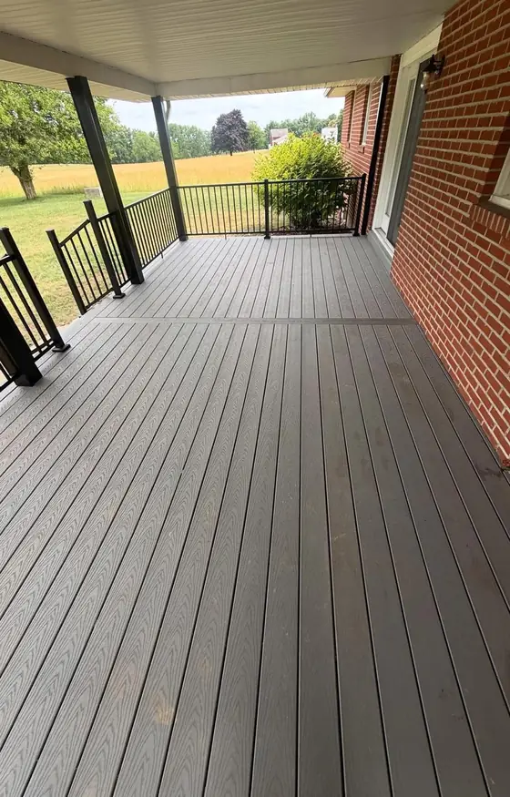 Long covered porch with gray composite decking and a black railing