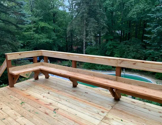 Wood deck with built in bench seating above a backyard pool