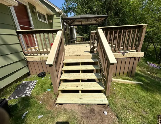 New wood deck stairs and railing leading to a backyard gazebo