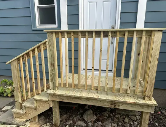 Side view of a new entry deck with steps and baluster railing