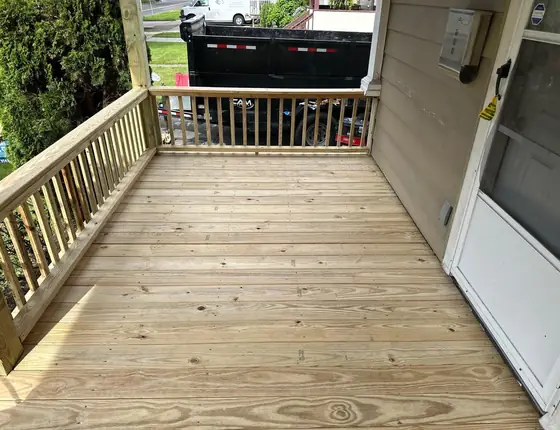 New wood porch deck with a railing beside a side door