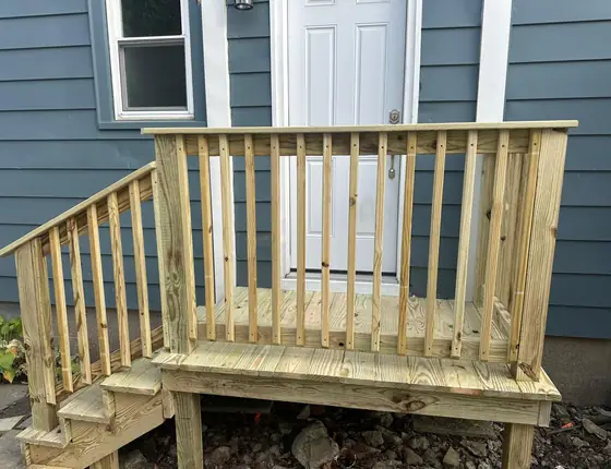 New side entry deck with railing and steps beside a blue sided home