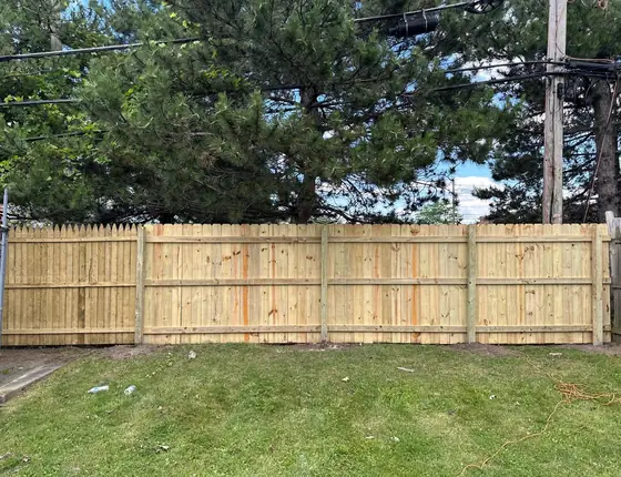 New wood fence with a decorative top in a backyard