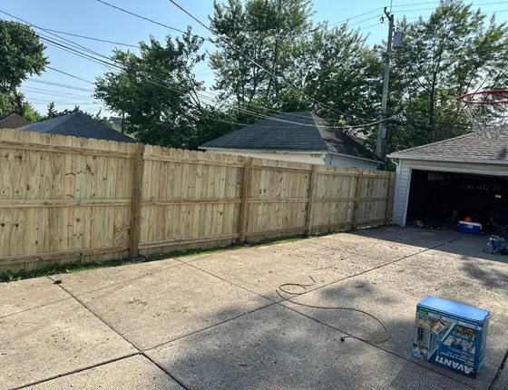 New wood fence beside a detached garage and driveway