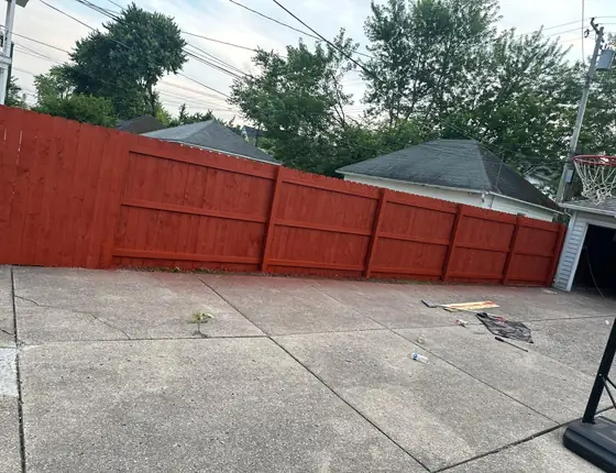 Red stained fence running beside a driveway