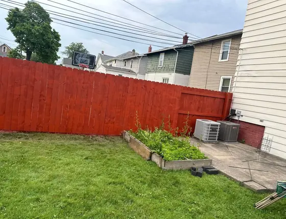 Red stained wood privacy fence along a backyard patio