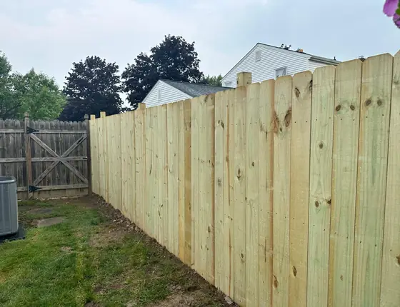 Six foot wood privacy fence with a gate and green yard