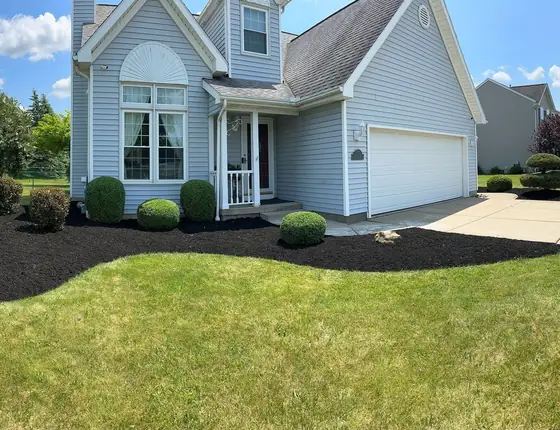 Black mulch bed curving along a blue sided home