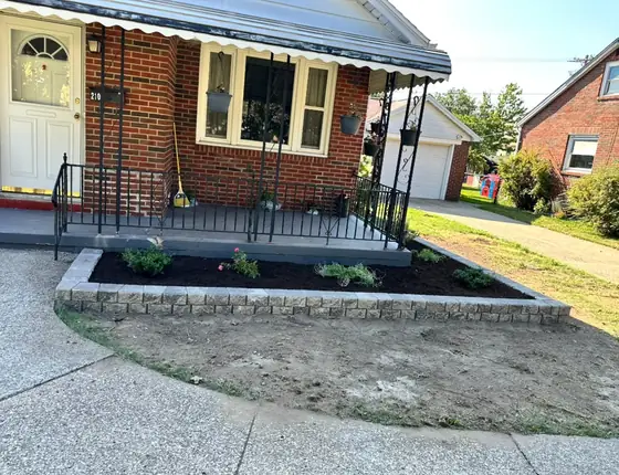 Newly planted garden bed with block edging at a front porch