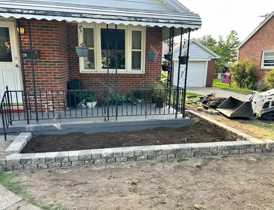 New stone block edged garden bed in front of a brick home