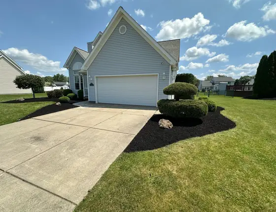Mowed lawn with trimmed shrubs around a corner home
