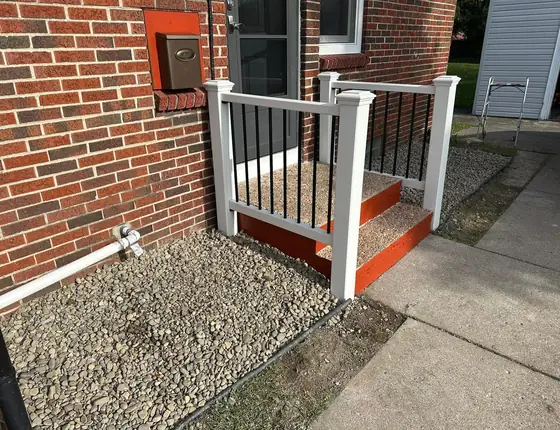 Entry steps with a white railing at a brick home