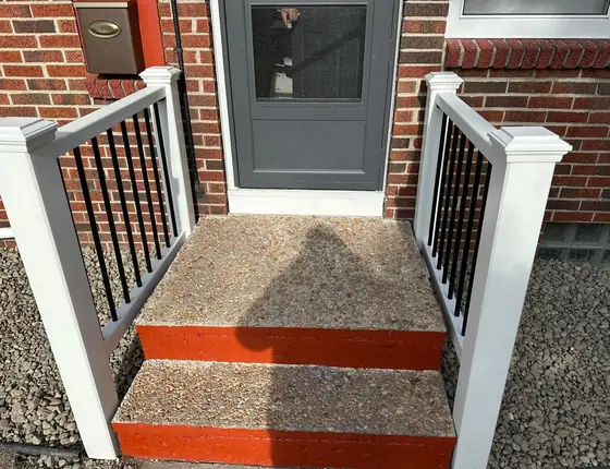Front steps with painted red risers and a white railing