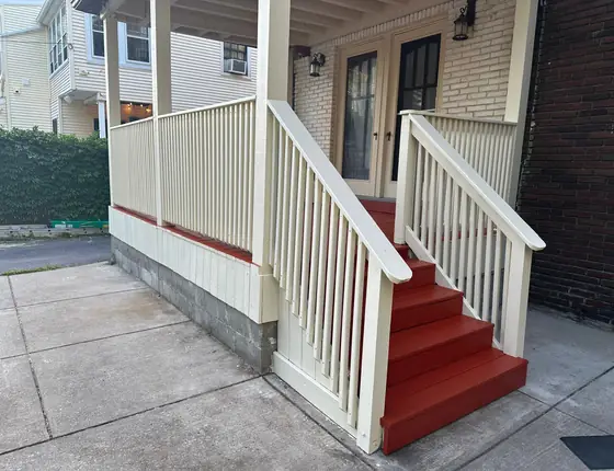 Front porch with a cream railing and red painted steps
