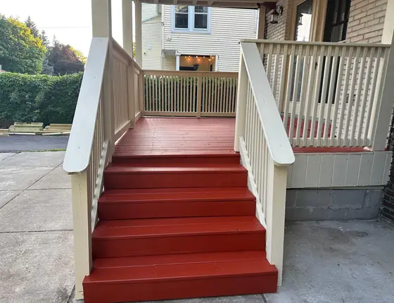 Porch steps painted red with a white railing and picket guard