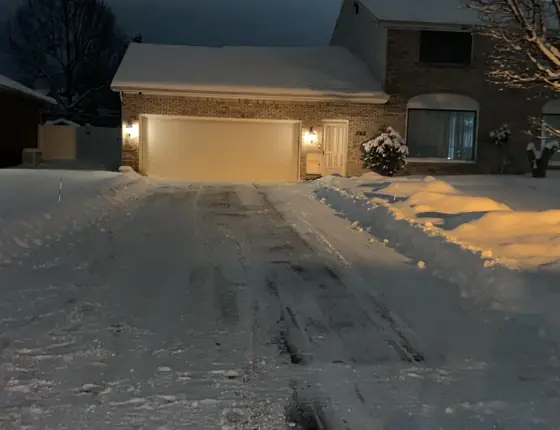 Driveway plowed at dusk with snow banks on each side