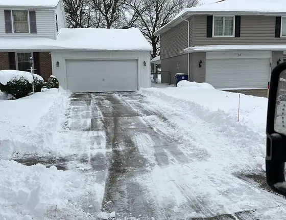 Driveway plowed between snow banks seen from the truck mirror