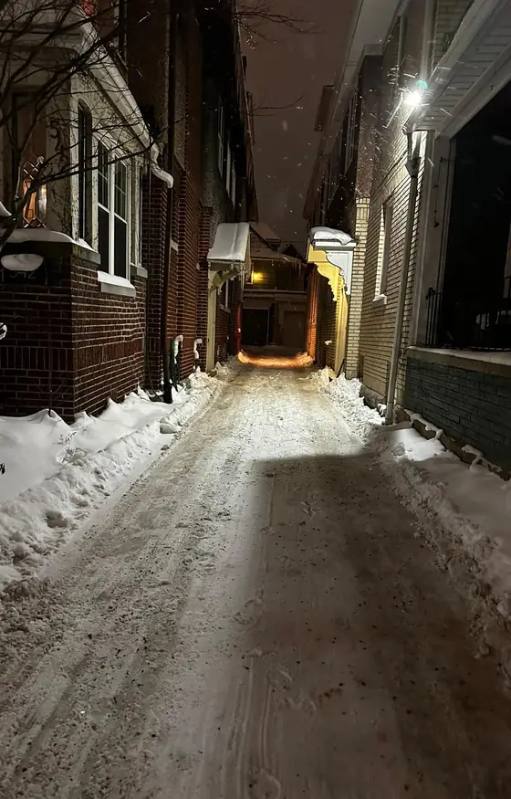 Narrow driveway cleared at night between buildings