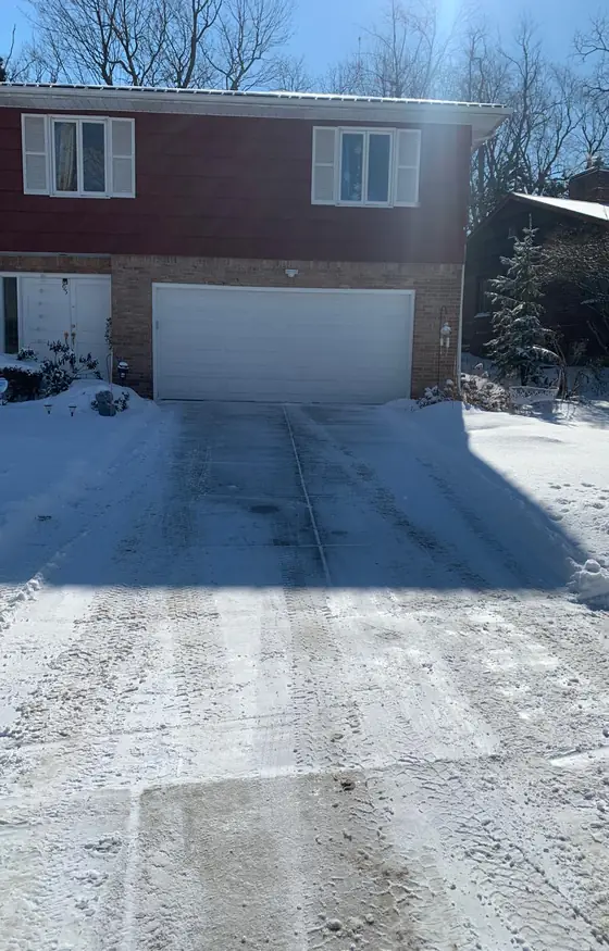 Plowed driveway at a brick home with an attached garage