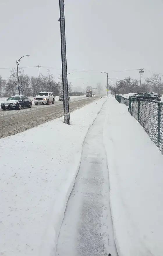 Sidewalk cleared along a busy road after heavy snow